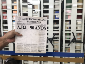 Foto de mão segurando a capa do livro "ABI 90 Anos" de Nelson Cadena